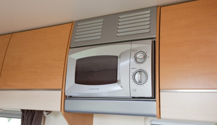 Kitchen cabinetwork houses integral microwave oven