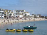 The harbour beach at St Ives with The Wharf behind and boats for hire in the foreground – all you need for a perfect day on the beach during your Cornish caravan holiday