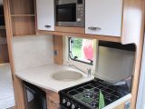 The optional microwave oven in the Sprite Quattro EW's kitchen is joined by black-front oven and fridge, and cream veneer locker doors