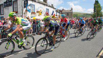 The Tour de France peloton passes through Kettlewell in the Yorkshire Dales, the sun shining and the crowds cheering