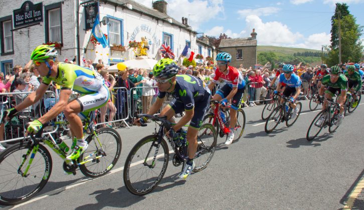 The Tour de France peloton passes through Kettlewell in the Yorkshire Dales, the sun shining and the crowds cheering