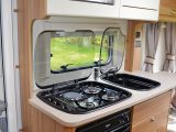 The kitchen in the Elddis Sanremo 304 offers a hob with three gas burners and an electric hotplate, plus  a combined oven and grill and a separate microwave oven