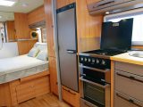 A wardrobe separates the bedroom from the kitchen, where the kit comprises a large fridge/freezer and separate oven and grill in the Hymer Nova GL 590