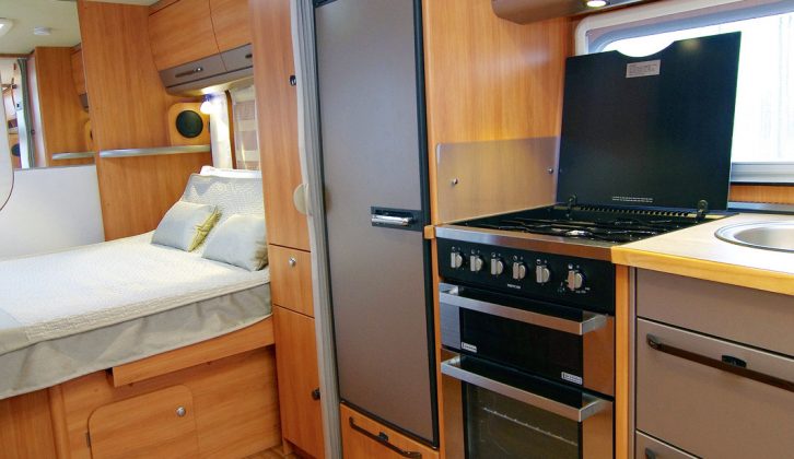 A wardrobe separates the bedroom from the kitchen, where the kit comprises a large fridge/freezer and separate oven and grill in the Hymer Nova GL 590