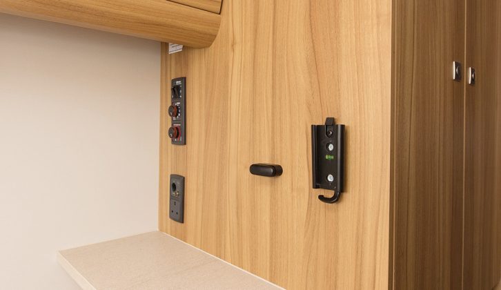 A TV stand with power and aerial points faces the front lounge in the Xplore 434 caravan