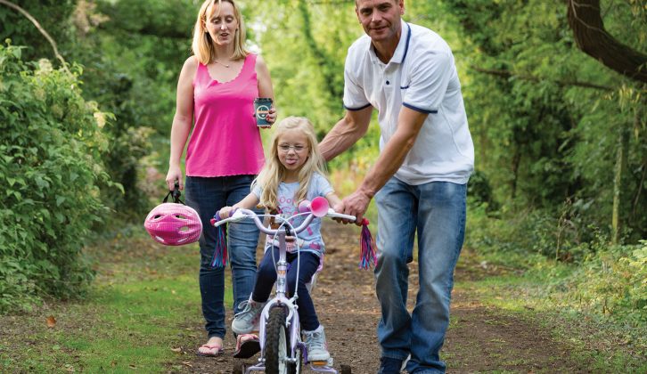 Stacie and Brian teach their daughter Isabelle how to ride a bike in the Cotswolds