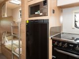 The microwave is at a sensible height above the tall, family-sized fridge/freezer, while the cooker has a dual-fuel hob plus separate oven and grill