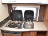 The three-burner gas hob and the sink are set within a steel unit, and both have glass lids to increase food preparation space