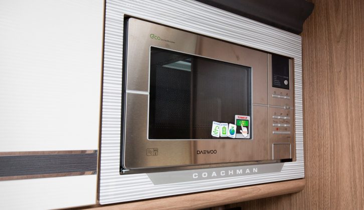 The microwave in its stylish surround is set above the dual-fuel hob, and the separate oven and grill
