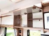 The large latched kitchen cupboard in this Bailey caravan is shelved and has handy crockery racks