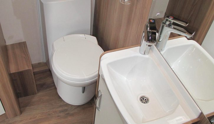 The sink, with a mirror behind and a shelved cupboard beneath, is in the middle of the washroom