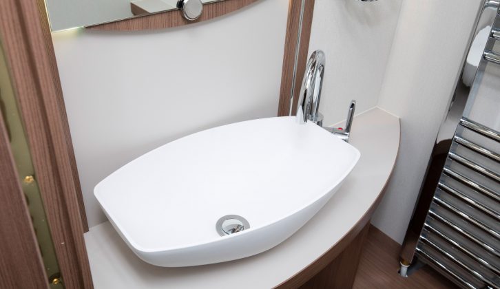 The sink has a mirror and a pair of toothmugs above, and storage below