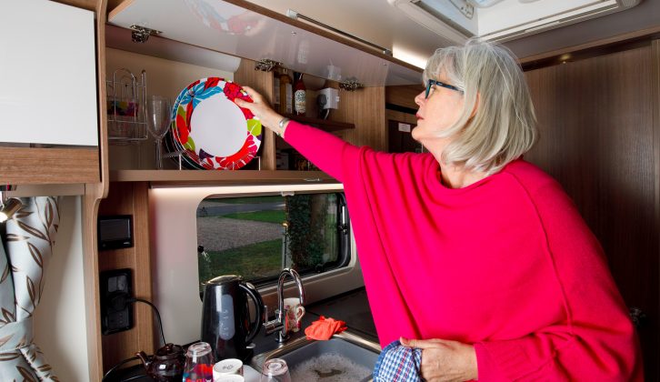 Behind a long, single cupboard door, is a good amount of overhead storage, with racking on the left and shelving on the right