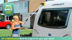 A caravan being cleaned with a long-handled brush