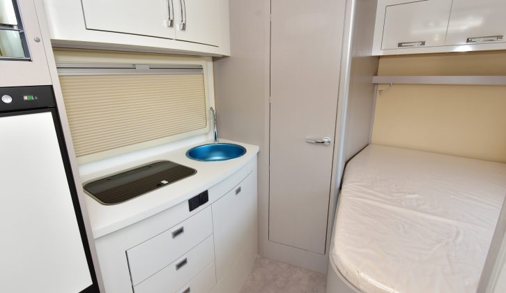 The offside kitchen is opposite the fixed double bed – the sink has blue protective cellophane covering it in our photos