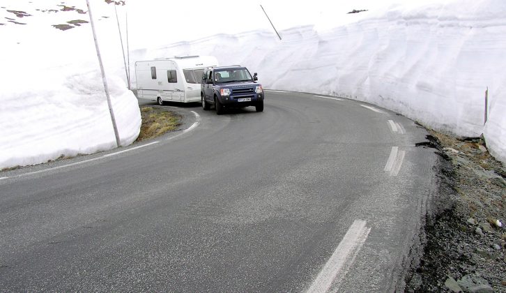 The caravan is dwarfed by the mounds of snow on either side of the road during their epic Nordic adventure