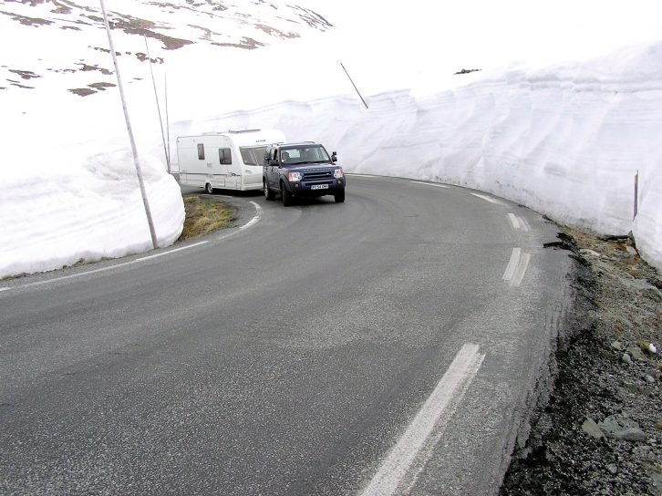 The caravan is dwarfed by the mounds of snow on either side of the road during their epic Nordic adventure