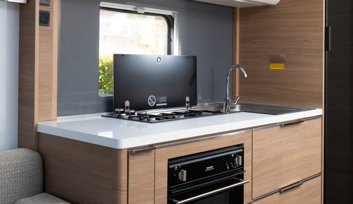 The generous kitchen features a three-burner hob and separate oven and grill, plus a microwave hidden in the overhead cupboard