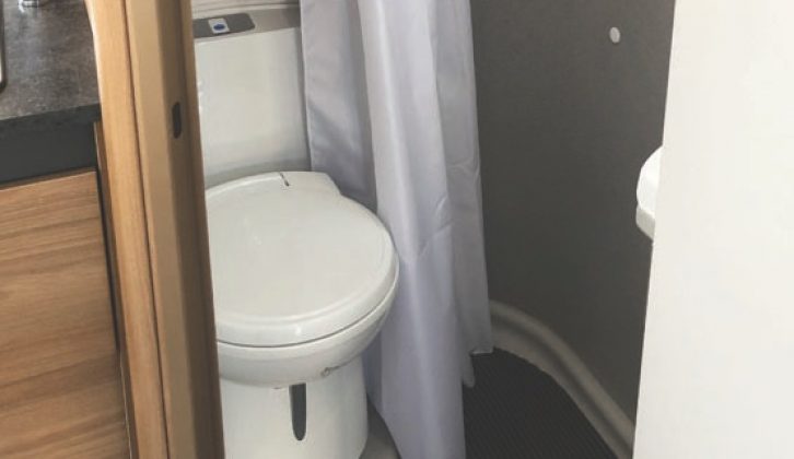 The corner washroom is compact, with a shower curtain and no window