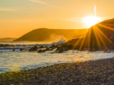 Spectacular sunset scene on rocky and misty beach near Tenby on Pembrokeshire coast