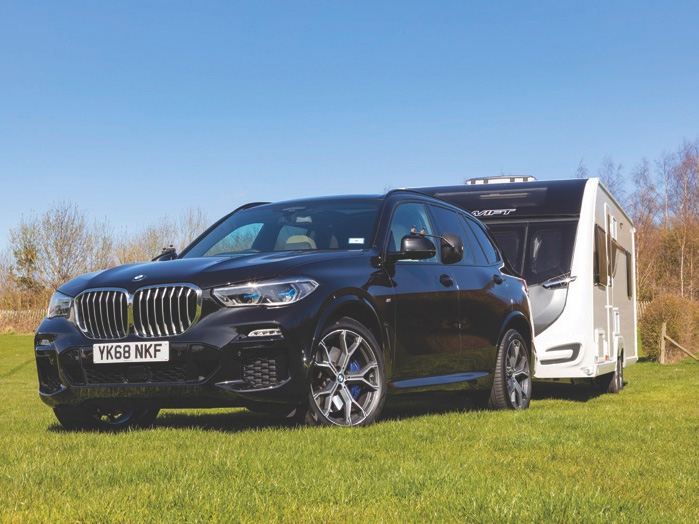 The BMW X5 parked on grass with a Swift caravan