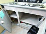 Shelved cupboards underneath the combined sink and two-burner gas hob