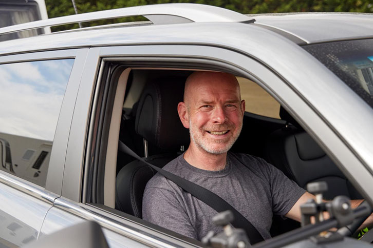 Man smiling from drivers seat of a towcar