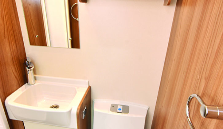 Washroom is well-appointed, with electric flush toilet and lighting above the wall mirror