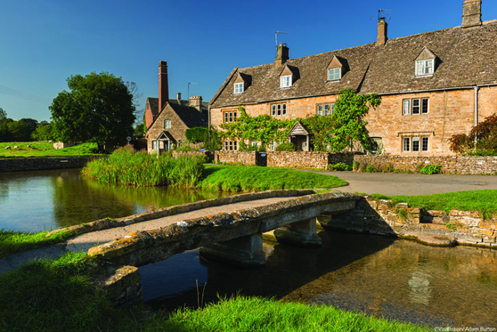 Traditional Cotswold stone cottages and stone footbridge in the Cotswolds village of Lower Slaughter.