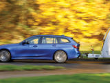A blue tow car pulling a caravan against a blurred autumnal backdrop