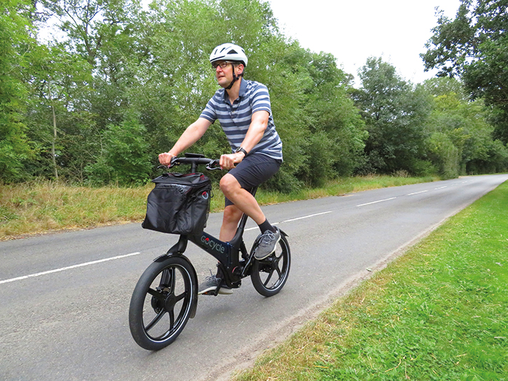 A man riding the GoCycle G4 down a quiet road