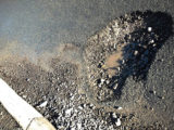 A pothole in the road with water in