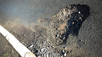 A pothole in the road with water in