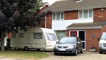 A car and caravan parked up outside a house