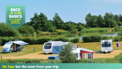 A picturesque setting with caravans parked up, water in the background and lots of trees
