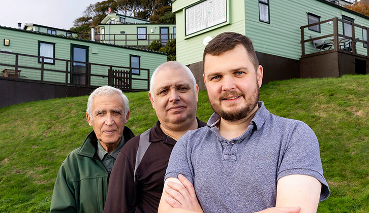 Three people standing in front of static caravans