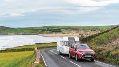 A red car towing a caravan in Devon