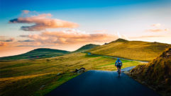 A person cycling along a pathway with a sun set and beautiful countryside ahead of him