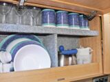 Caravan kitchen cupboards loaded with crockery and cups