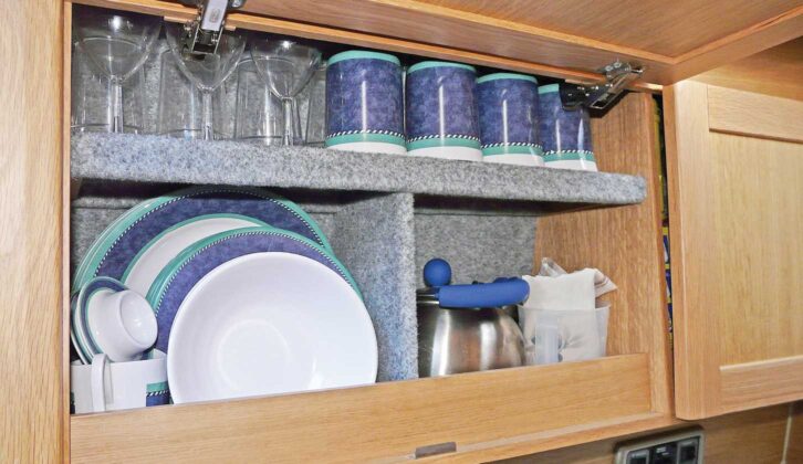 Caravan kitchen cupboards loaded with crockery and cups