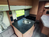 Compact kitchen is well-lit and has a four-burner gas hob and a separate oven and grill