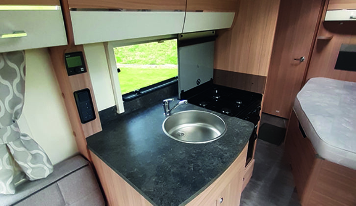 Compact kitchen is well-lit and has a four-burner gas hob and a separate oven and grill