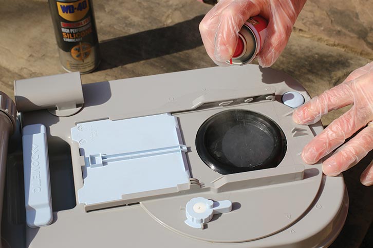 Spray the top of the toilet blade with some of the silicone lubricant