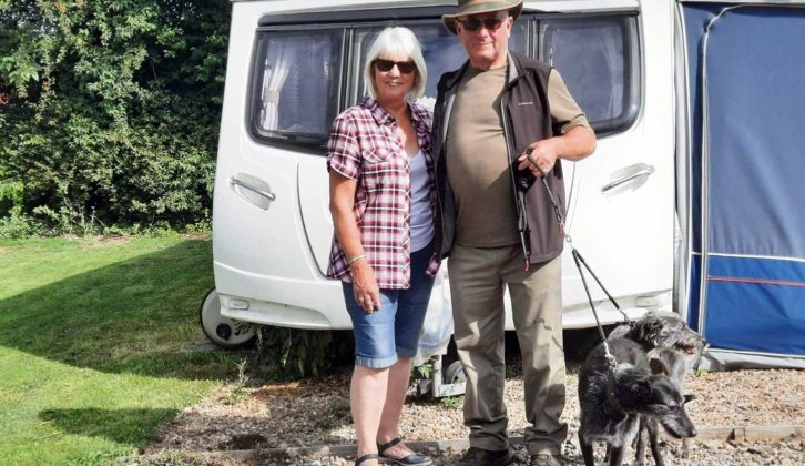 Man and woman by caravan holding lead of two dogs