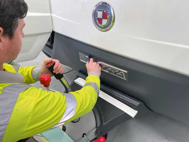 Person positioning the model’s ‘Xtra’ badge