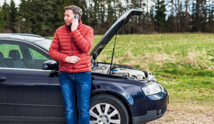 Man standing by broken down car