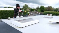 A man cleaning the roof of a caravan with a hose