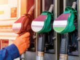 Hand reaching for pumps at a fuel station