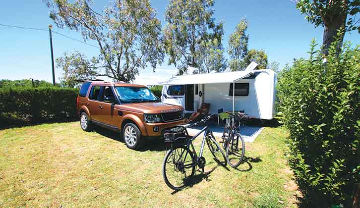A canopy on a caravan by a tow car on a pitch