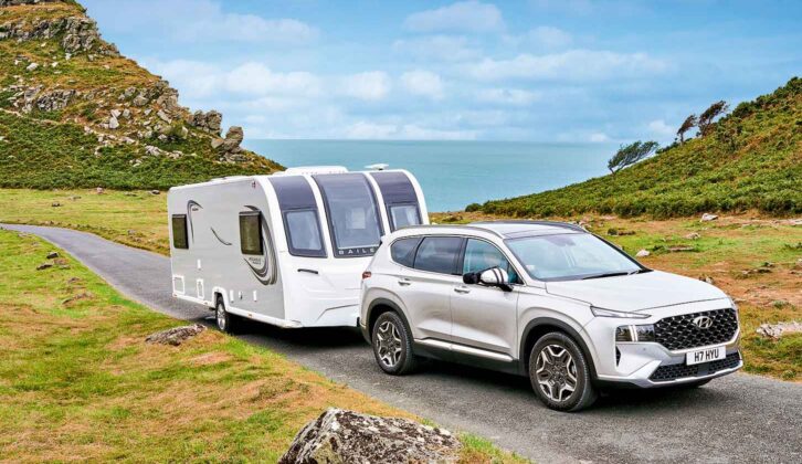 A car towing a caravan with the sea in the background